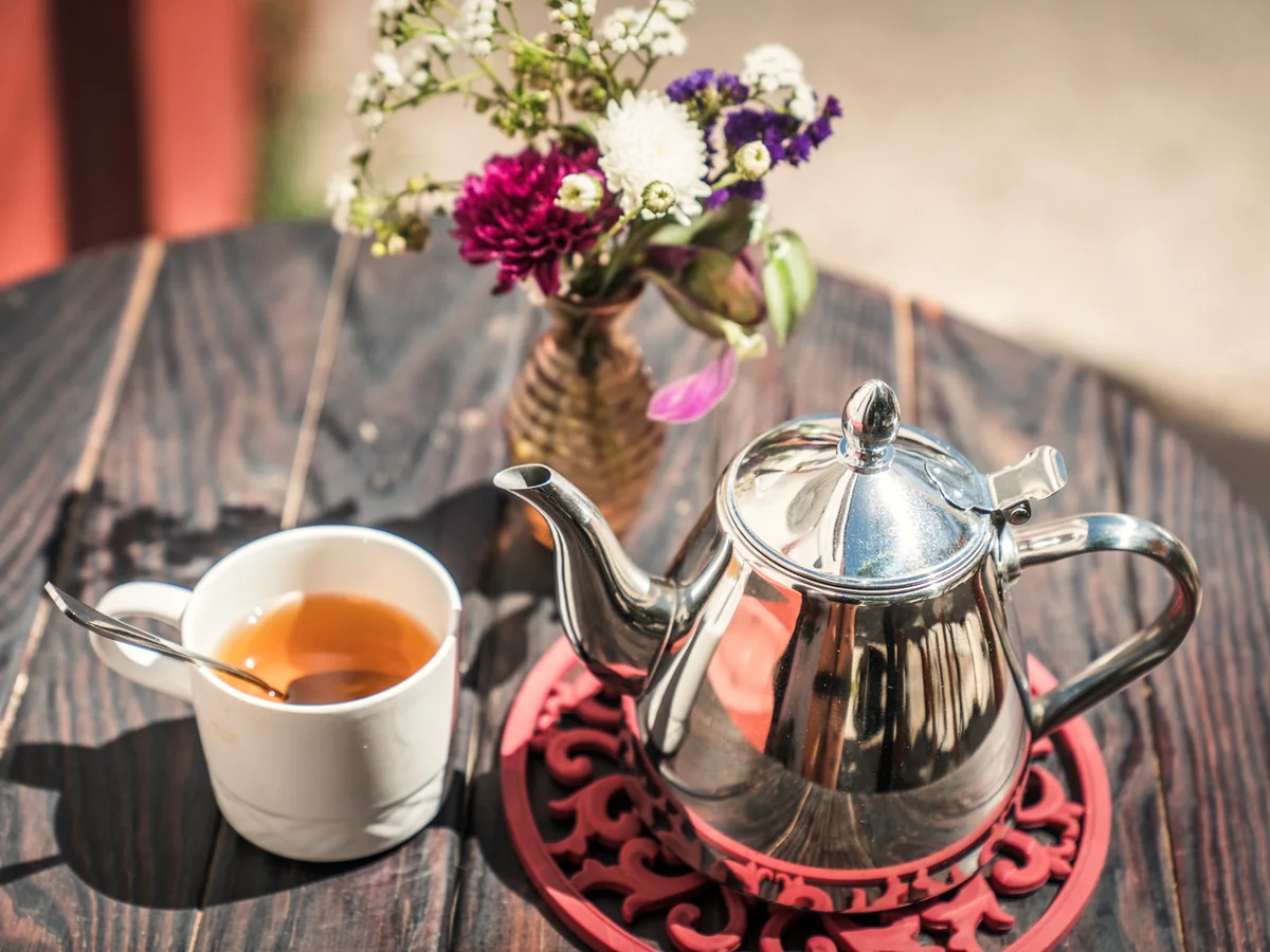 Té y flores sobre una mesa exterior.