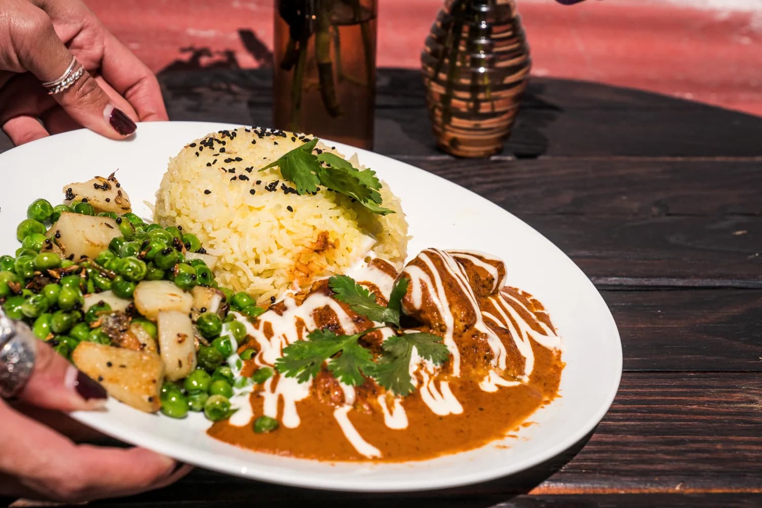 A curry plate arrives at a wooden table.
