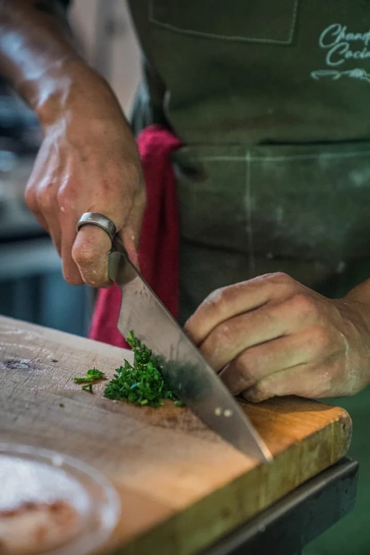 Hands chop fresh herbs in the kitchen.